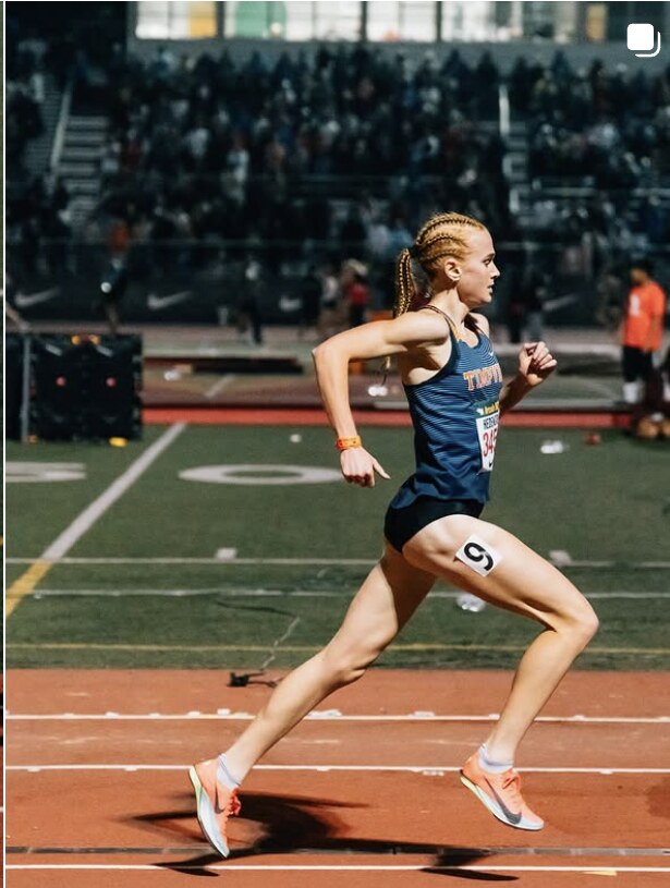 Middle-distance runner rounding the turn under the lights